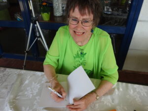 Barbara Harry signing a copy of Oasis: Soul Refreshing at the October 2024 book launch—an inspirational parable inviting spiritual renewal.